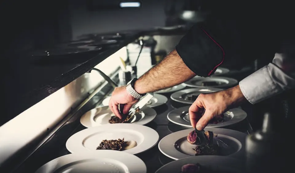 Mains du chef dressant les assiettes au passe