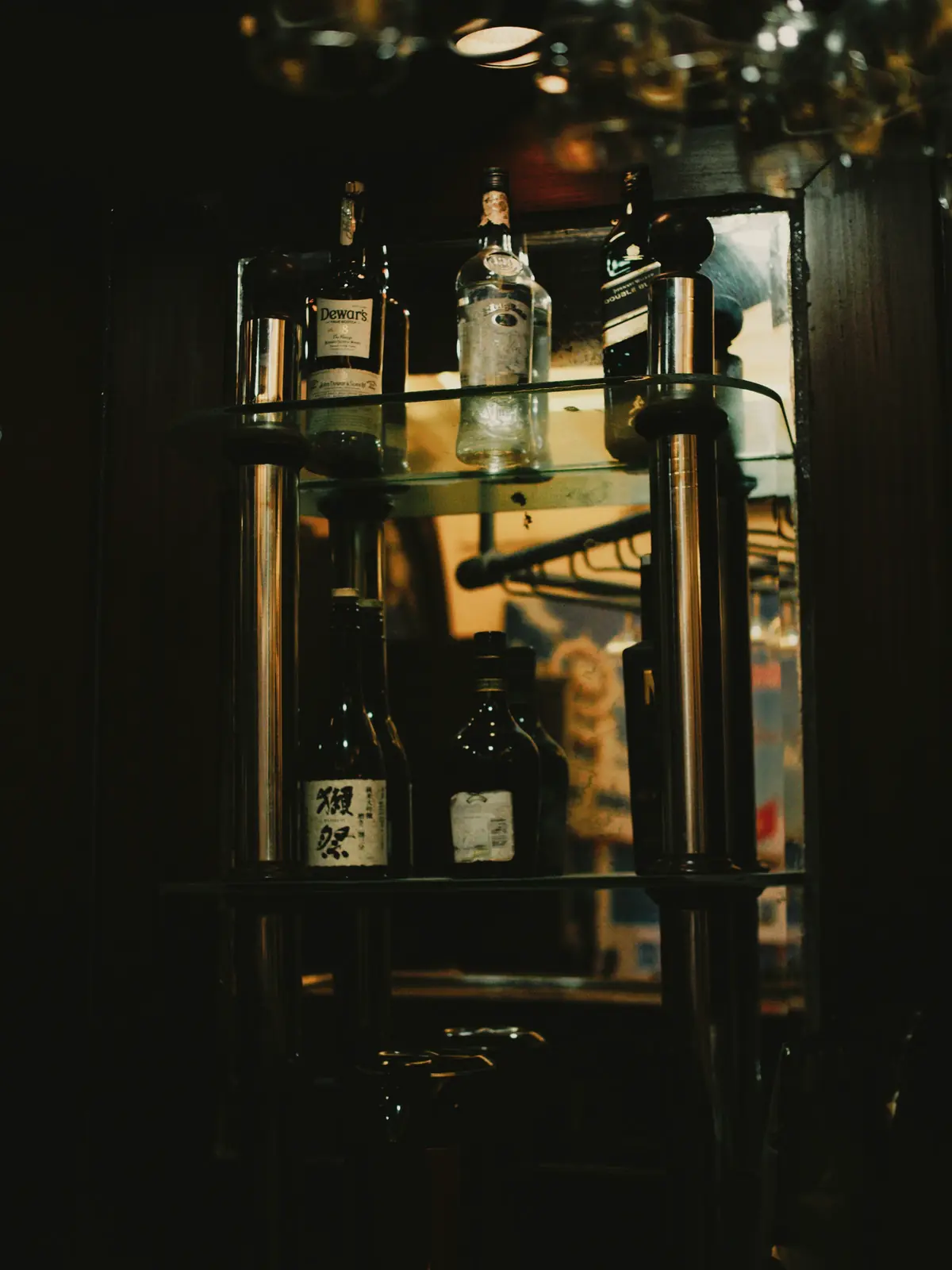 Bouteilles sur deux étagères dans un bar tamisé