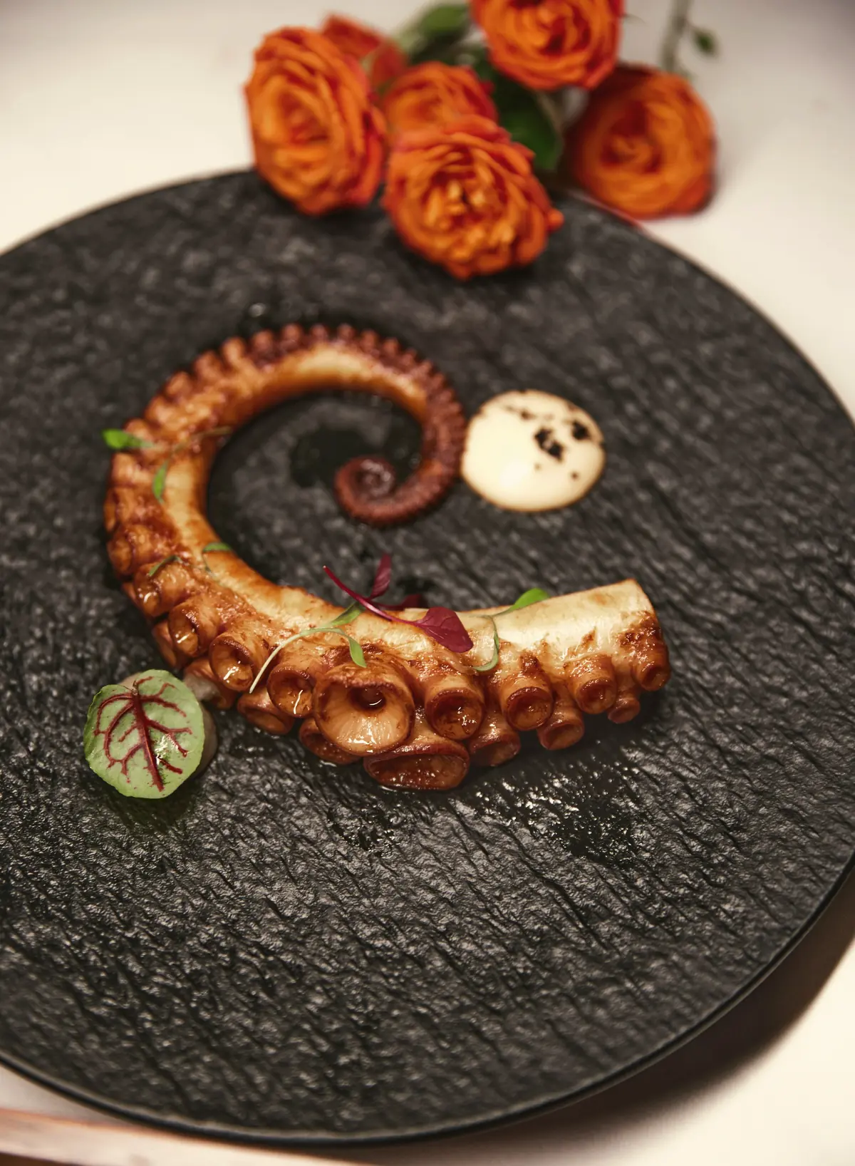 Tentacule de poulpe grillé sur une assiette noire